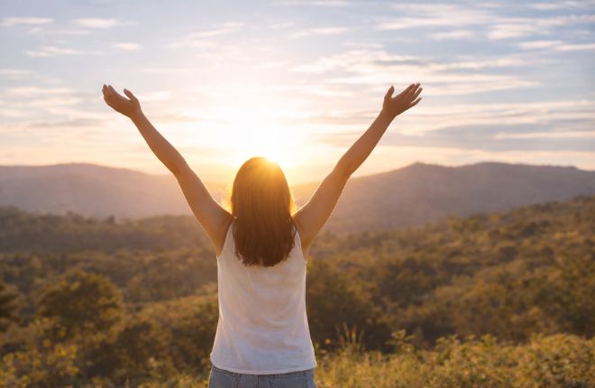 太陽に向かって万歳をする女性
